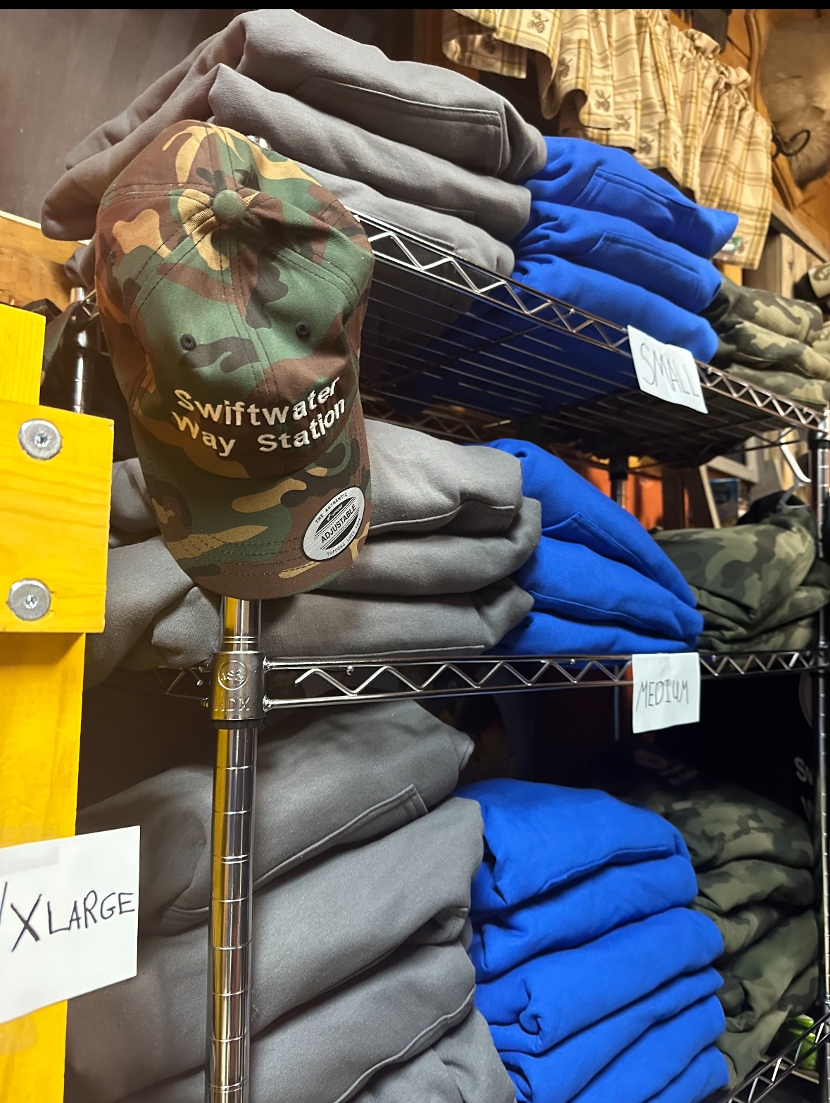 Swiftwater Way Station hoodies and camo hat merch display